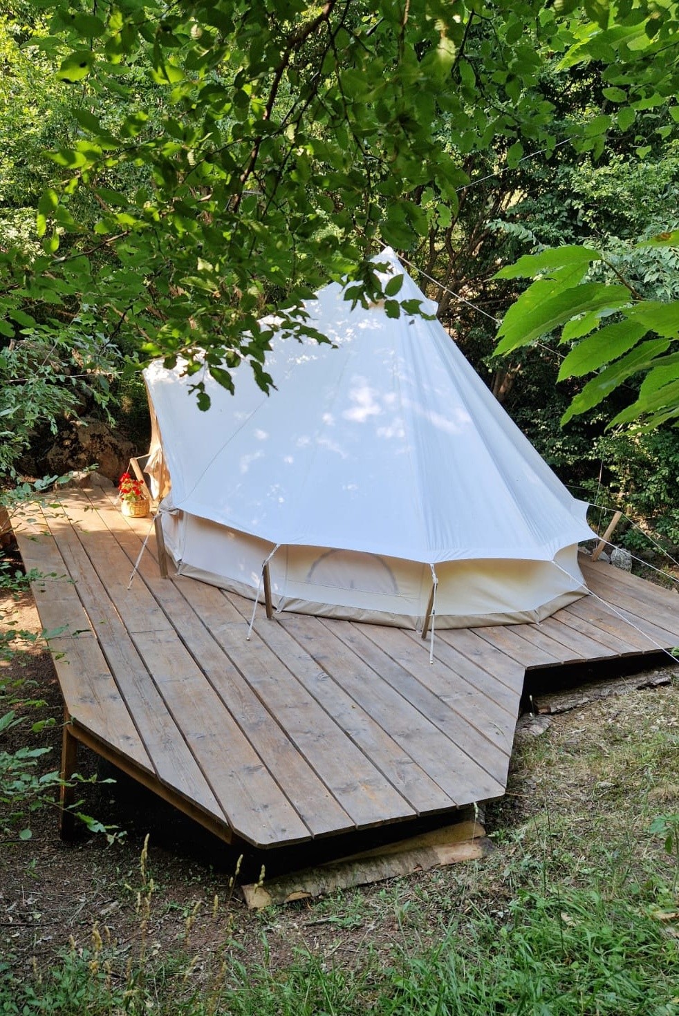 Holzplattform mit Terrasse und Sitzbereich neben dem Glamping-Zelt